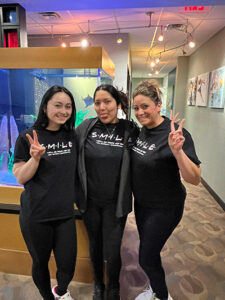 Dental team members in playful SMILE t-shirts near an aquarium